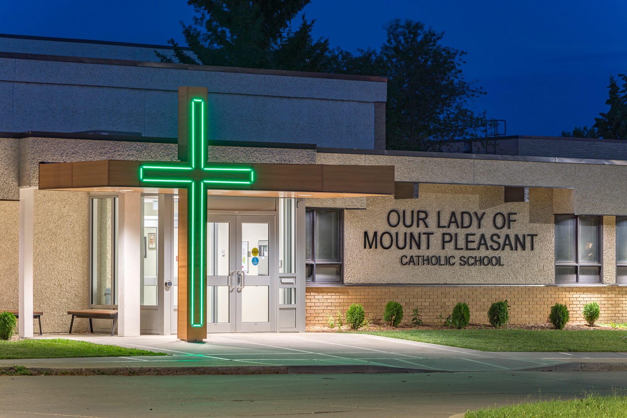 Our Lady of Mount Pleasant School exterior front entrance with cross glowing green at night